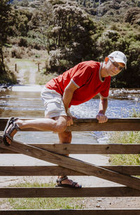 Full length of man climbing on wooden gate