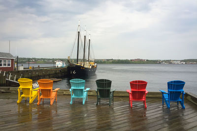 Chairs and tables by sea against sky