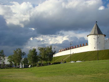 Trees and buildings on field against sky