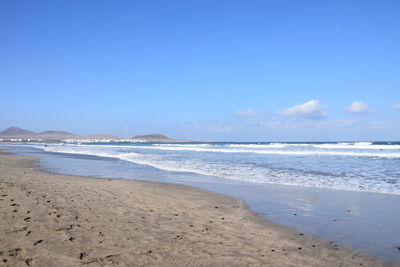 Scenic view of beach against blue sky