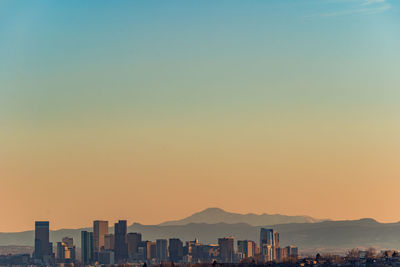 Buildings in city against clear sky during sunset