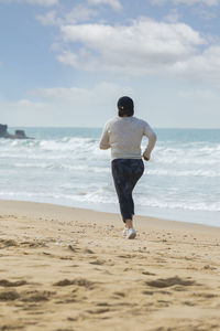 Rear view of man on beach against sky