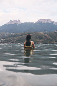 Rear view of woman swimming in lake against sky