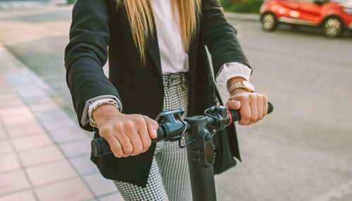 Midsection of businesswoman riding electric push scooter on sidewalk