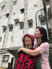 Portrait of woman hugging mother in city