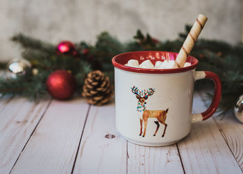 Cup of hot chocolate on white wooden background with christmas decor.