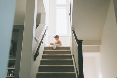 Rear view of boy standing on staircase at home