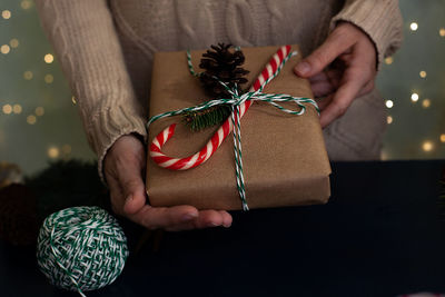 Woman wraps a handmade eco style christmas present in kraft paper and natural spruce branches