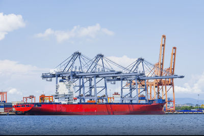 Cranes at commercial dock against sky