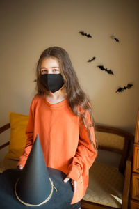 Portrait of cute girl wearing mask sitting at home