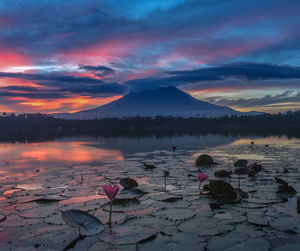 Scenic view of lake by mountains against sky during sunset