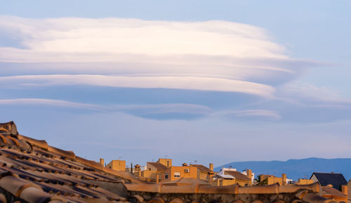 Low angle view of buildings against sky with lenticular clouds 