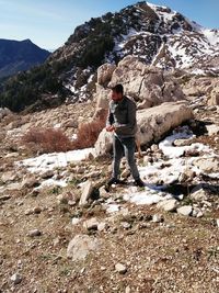 Rear view of man standing on rock against sky