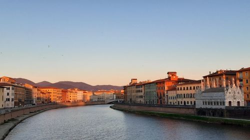 Buildings by river against clear sky