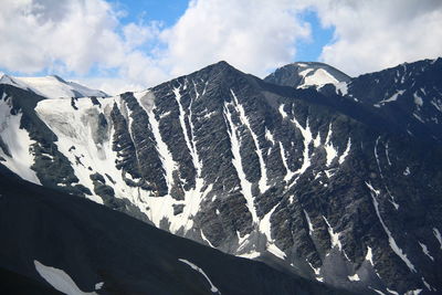 Dark rocky mountains with snow in altai in summer in fine weather