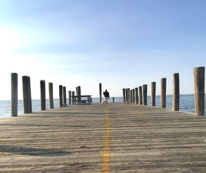 Wooden posts on pier over sea against sky
