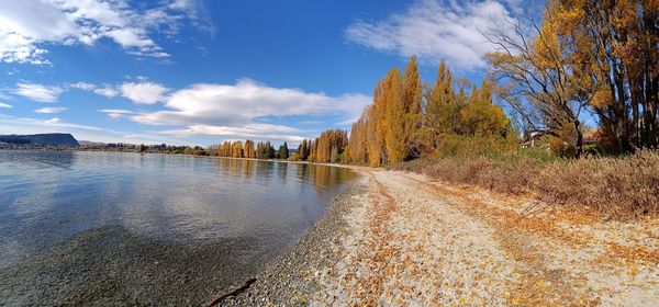 Panoramic shot of water flowing by trees against sky