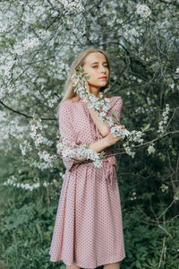 Blonde girl on a spring walk in the garden with cherry blossoms. female portrait, close-up. 