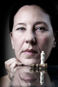 Close-up portrait of woman with chess pieces on table