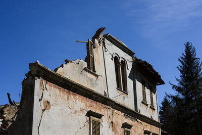 Low angle view of bird perching on old building against sky