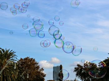 Low angle view of bubbles against rainbow in sky
