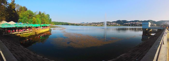 Built structure by river against clear blue sky