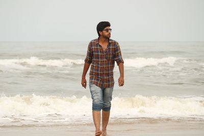 Full length of man walking on shore at beach against sky