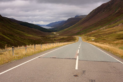 Empty road amidst mountains against sky