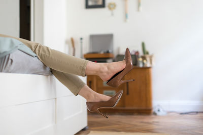 Low section of woman wearing stilettos relaxing on bed at home