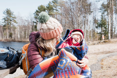 Mom cuddling her daughter who is laughing whilst having family picnic