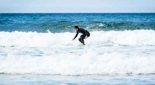 Man surfing in sea against sky