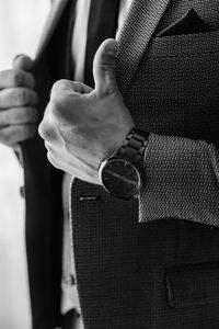 A man in a gray trouser suit three-piece with a white shirt and a black tie in a watch