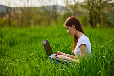 Woman using mobile phone while sitting on field