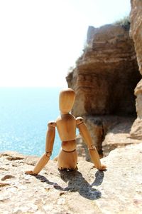 Close-up of wooden figurine on cliff against sea