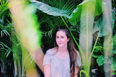 Portrait of young woman standing against plants