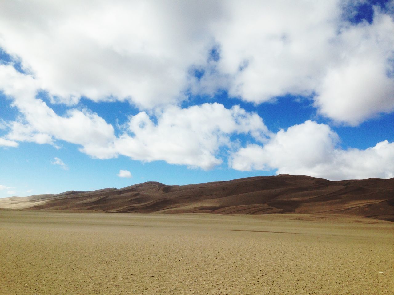 sky, landscape, tranquil scene, tranquility, desert, cloud - sky, sand, scenics, arid climate, cloud, nature, beauty in nature, mountain, cloudy, remote, barren, day, non-urban scene, horizon over land, blue