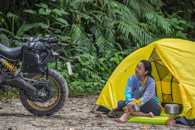 Woman relaxing at camp looking at her scrambler type motorcycle