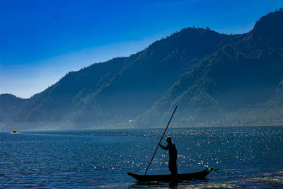 Man fishing in sea against sky