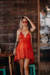 Portrait of young woman wearing sunglasses while standing in cafe