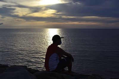 Rear view of man looking at sea against sky