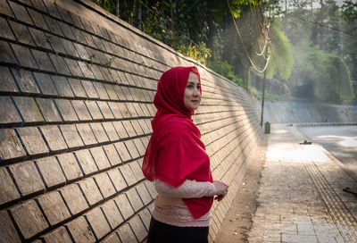 Portrait of woman standing on footpath