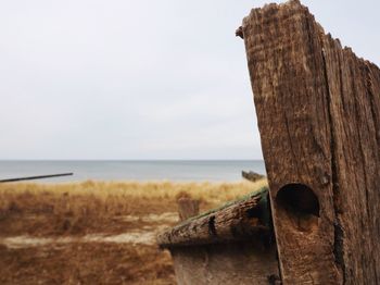 Close-up of wooden post at beach against sky