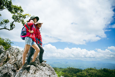 Rear view of woman standing on mountain against sky