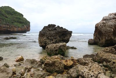 Rocks on sea shore against sky