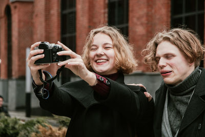 Happy friends photographing themselves with digital camera