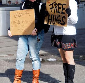 Midsection of women holding placards while standing on city street