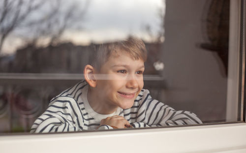 Smiling boy looking through window