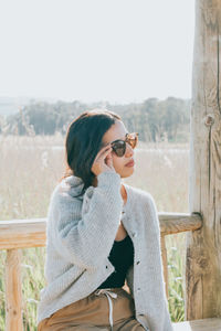 Young woman wearing sunglasses while sitting on bench