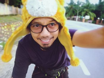 Portrait of smiling young man wearing yellow hat on road