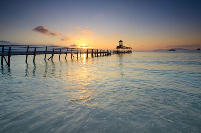 Silhouette pier over sea against sky during sunset